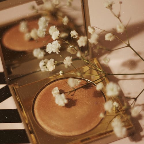 Une fleur blanche posée sur le rebord d'une fontaine, reliée à un petit miroir.