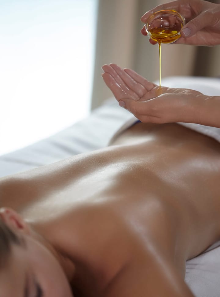 Une main verse une huile dans on autre main pour faire un massage.