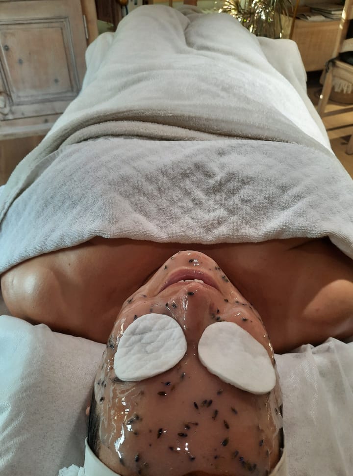 Une femme se repose avec un masque hydratant couchée sur un lit.